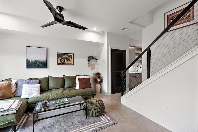 living area with baseboards, visible vents, ceiling fan, stairs, and concrete flooring