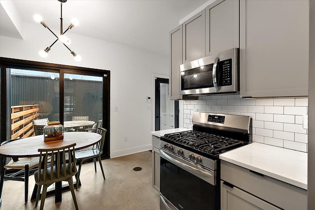 kitchen with stainless steel appliances, gray cabinets, backsplash, finished concrete floors, and baseboards