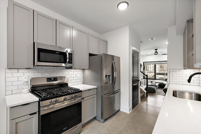 kitchen featuring appliances with stainless steel finishes, gray cabinets, light countertops, and a sink