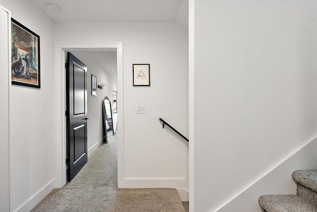 hallway with stairs, baseboards, carpet flooring, and an upstairs landing