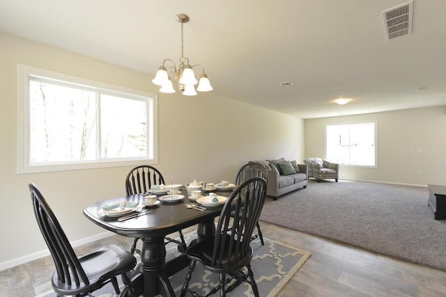 dining area with a notable chandelier, light wood-style floors, visible vents, and baseboards