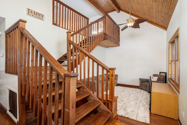 stairs featuring ceiling fan, high vaulted ceiling, wood finished floors, baseboards, and beam ceiling