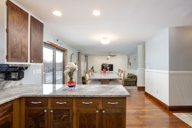 kitchen with a wainscoted wall, recessed lighting, ceiling fan, wood finished floors, and a peninsula