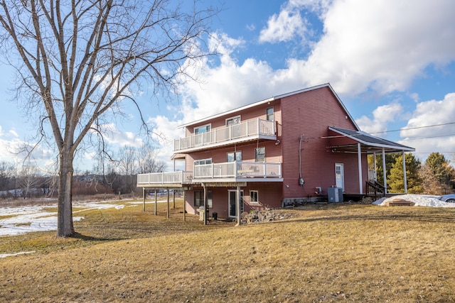 rear view of house featuring a balcony, central AC, and a lawn