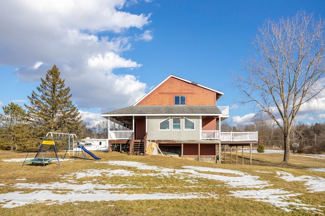 view of front of property featuring a shingled roof, a playground, and a wooden deck