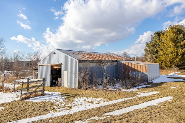 snow covered structure featuring a pole building and an outdoor structure