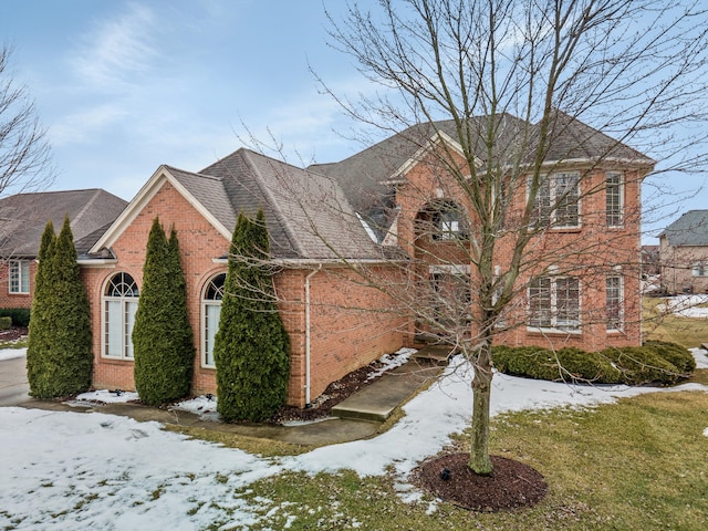 view of front of home featuring brick siding and roof with shingles