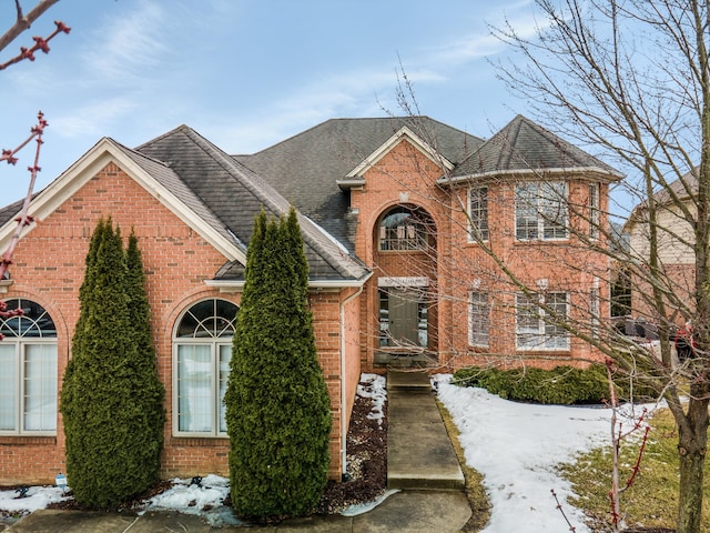 traditional-style home featuring brick siding and roof with shingles