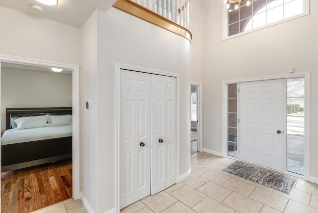 foyer entrance with light tile patterned floors, a high ceiling, and baseboards