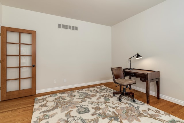 office featuring light wood-type flooring, visible vents, and baseboards