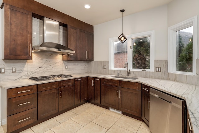 kitchen with wall chimney exhaust hood, tasteful backsplash, a sink, and stainless steel appliances