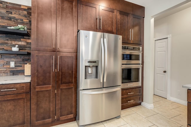 kitchen featuring light tile patterned floors, dark brown cabinetry, stainless steel appliances, baseboards, and light countertops