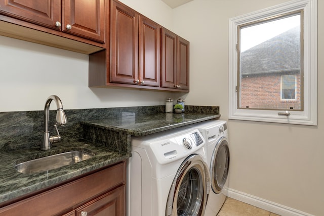 washroom with light tile patterned floors, a sink, baseboards, cabinet space, and washing machine and clothes dryer