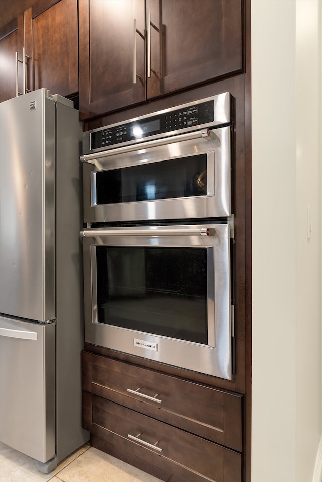 details with appliances with stainless steel finishes and dark brown cabinetry