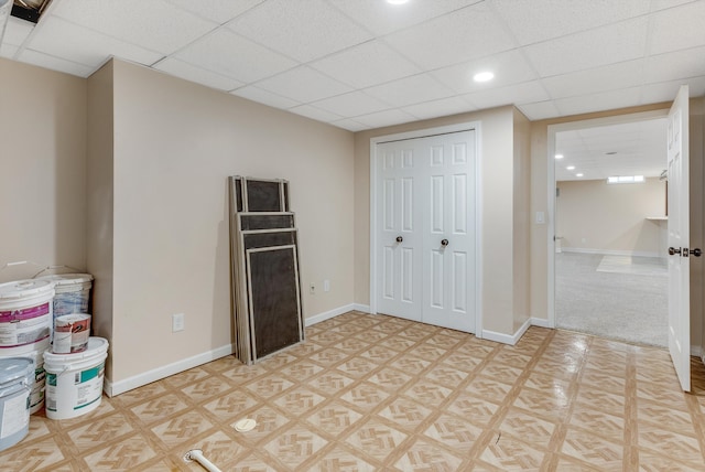 unfurnished bedroom with a paneled ceiling, a closet, baseboards, and recessed lighting