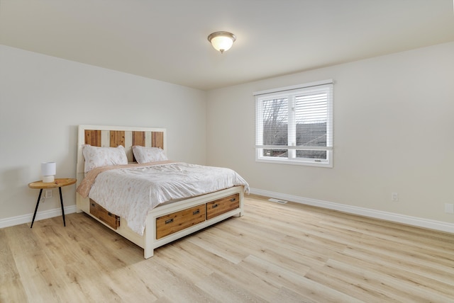 bedroom featuring visible vents, light wood-style flooring, and baseboards