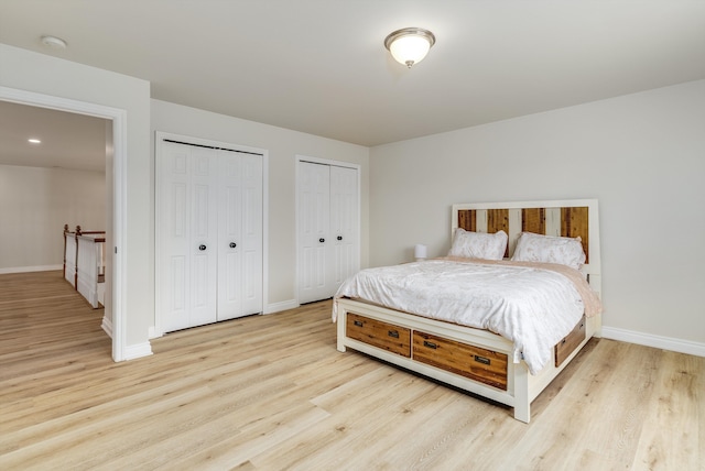 bedroom featuring baseboards, light wood finished floors, and multiple closets