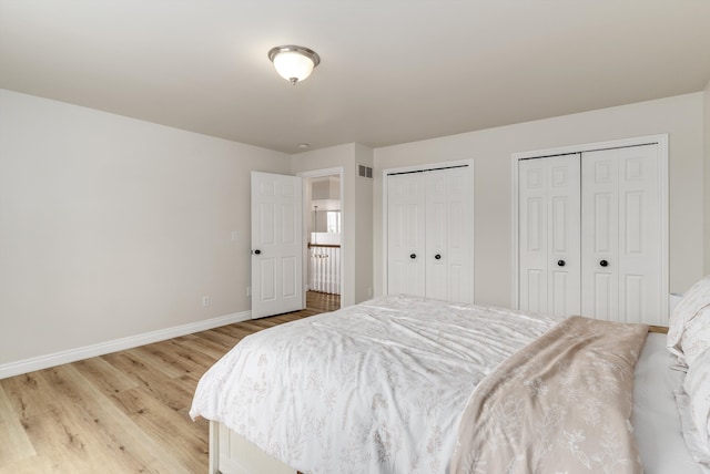 bedroom featuring light wood-style floors, visible vents, baseboards, and two closets