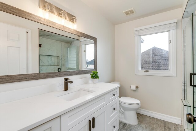 bathroom with visible vents, toilet, wood tiled floor, a shower stall, and vanity