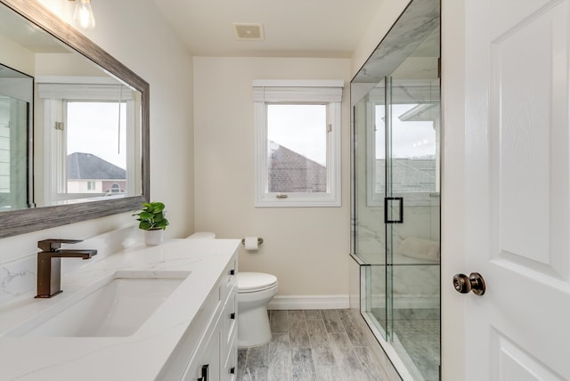 full bath featuring a marble finish shower, visible vents, toilet, wood finished floors, and vanity