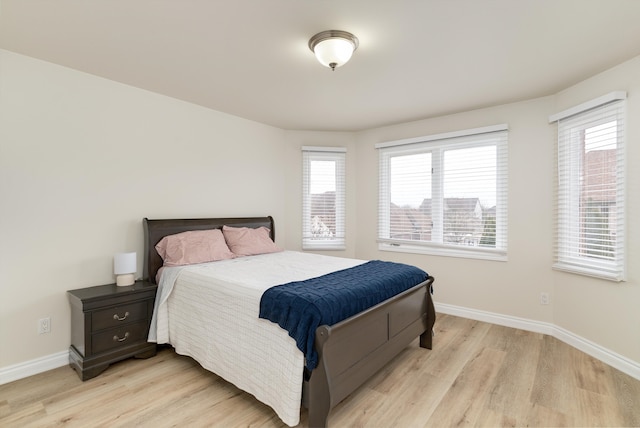 bedroom with light wood finished floors and baseboards