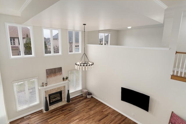 living room with a notable chandelier, a fireplace, wood finished floors, baseboards, and crown molding