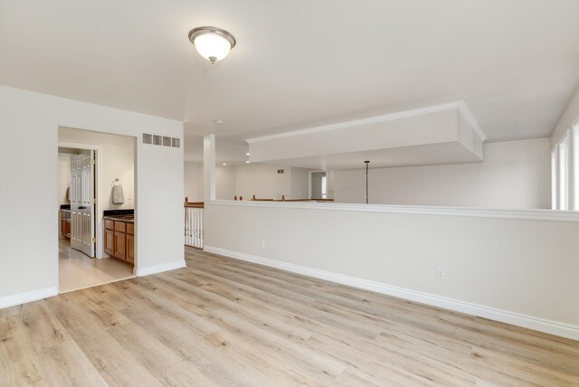 spare room featuring light wood-type flooring, visible vents, and baseboards