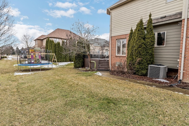 view of yard featuring a trampoline, a playground, and central air condition unit