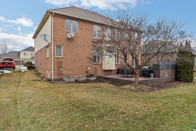 rear view of property with a yard, a patio, and brick siding