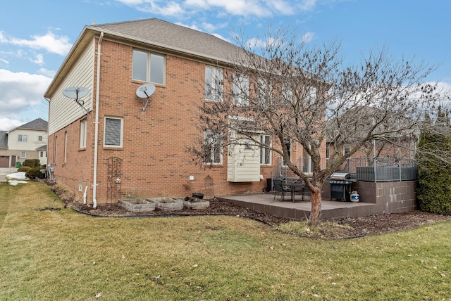 back of property featuring brick siding, a lawn, a patio area, and a shingled roof