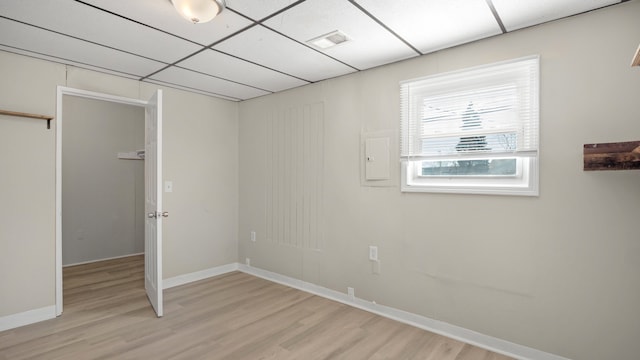 interior space featuring light wood-type flooring, visible vents, a paneled ceiling, and baseboards