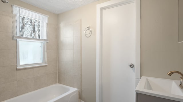 full bathroom with a healthy amount of sunlight, a textured ceiling, vanity, and bathtub / shower combination