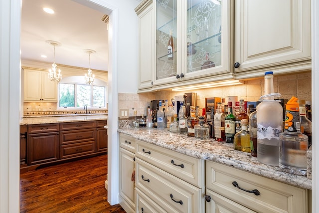 bar with a chandelier, dark wood-type flooring, a sink, backsplash, and decorative light fixtures