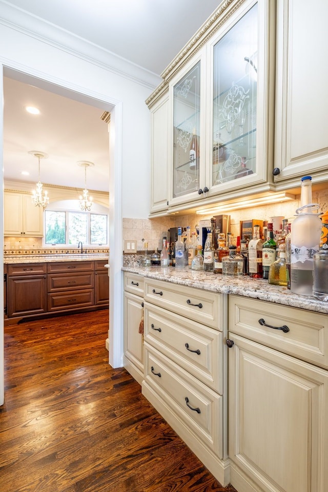 bar featuring a notable chandelier, tasteful backsplash, dark wood finished floors, decorative light fixtures, and crown molding