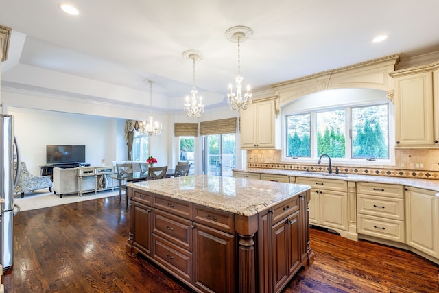 kitchen with tasteful backsplash, open floor plan, dark wood-style flooring, cream cabinetry, and a sink