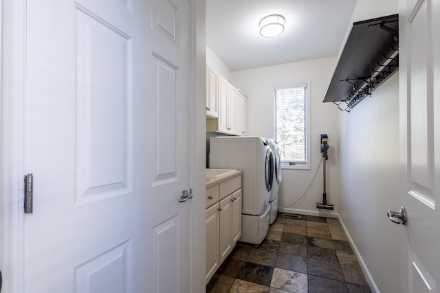 laundry area featuring stone finish flooring, cabinet space, independent washer and dryer, and baseboards