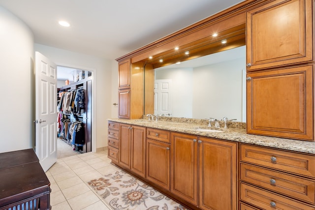 bathroom featuring double vanity, a spacious closet, a sink, and tile patterned floors