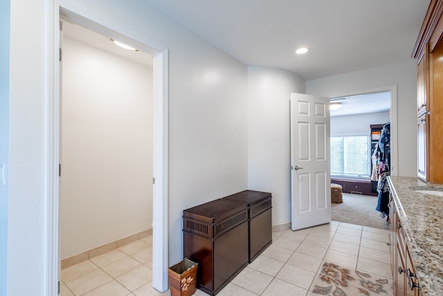 hallway with light carpet, baseboards, light tile patterned flooring, a sink, and recessed lighting