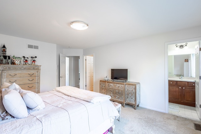 bedroom featuring light carpet, a sink, visible vents, baseboards, and ensuite bath