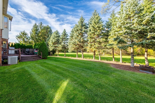 view of yard with central AC and a wooden deck