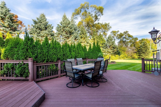 wooden deck with outdoor dining area and a yard