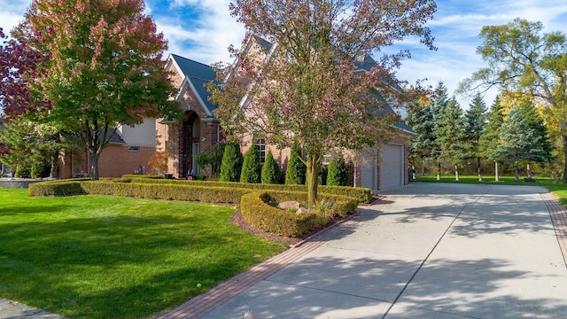 view of front of home with driveway, stone siding, an attached garage, a front yard, and brick siding