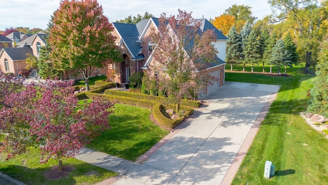 view of front of property with a front yard, concrete driveway, brick siding, and an attached garage