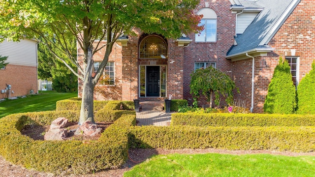 doorway to property featuring brick siding and a shingled roof