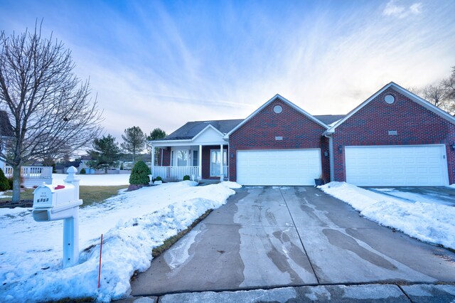 ranch-style home featuring a porch, brick siding, driveway, and an attached garage