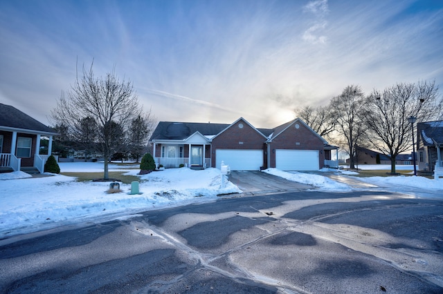 ranch-style house with a porch, brick siding, driveway, and an attached garage