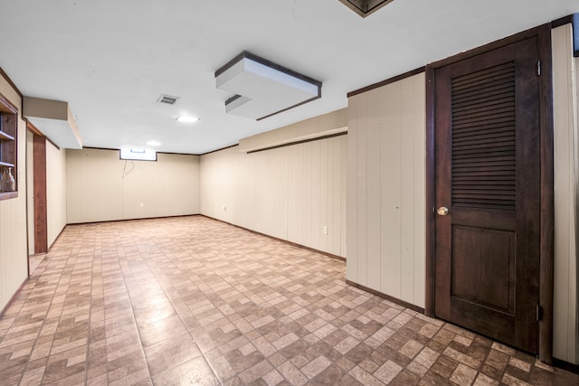 finished basement featuring visible vents, wooden walls, and baseboards