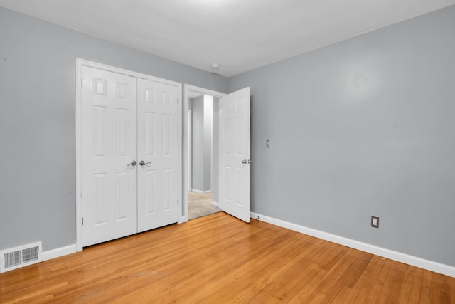 unfurnished bedroom featuring a closet, visible vents, light wood-style flooring, and baseboards