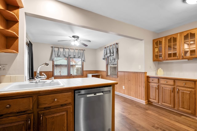 kitchen featuring a sink, brown cabinets, dishwasher, and wainscoting