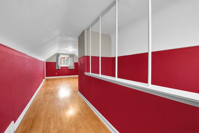 interior space featuring vaulted ceiling, hardwood / wood-style floors, and baseboards